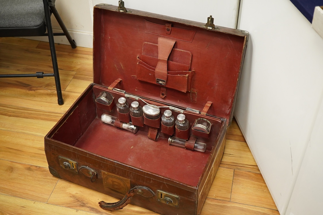 An early 20th century leather travelling toilet case, with 'Peninsular & Oriental Steam Navigation Compy' paper labels, containing eight French 950 standard white metal mounted glass toilet jars and one English silver mo